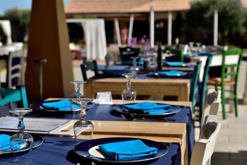 a group of tables with blue plates and wine glasses at Janna e Luna Resort in Agrustos