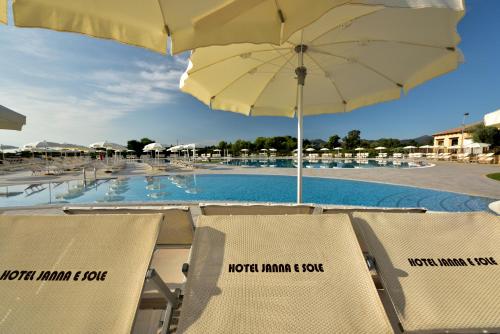 a group of chairs with an umbrella and a pool at Janna e Luna Resort in Agrustos