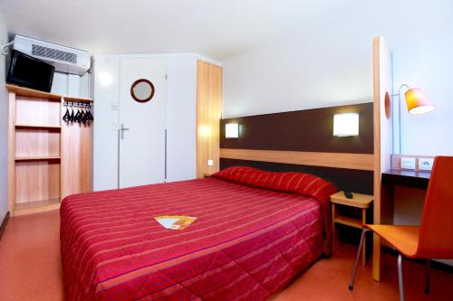 Cette chambre comprend un lit rouge et un bureau. dans l'établissement Premiere Classe Montpellier Sud Lattes, à Lattes