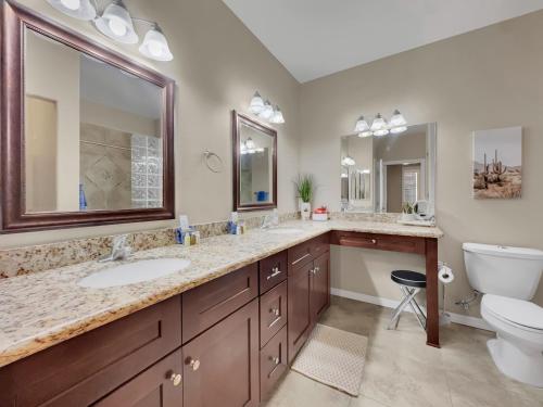 a bathroom with two sinks and a toilet and mirrors at Southern #1114 Mesa in Mesa