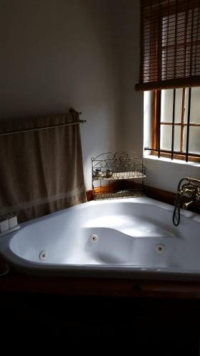 a white bath tub in a bathroom with a window at 33 On Loop, Flat 1 in Ladybrand