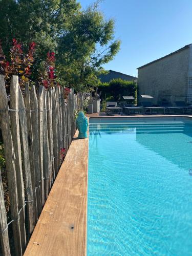 une piscine à côté d'une clôture en bois avec une eau bleue dans l'établissement Villa Whaou 5*, piscine chauffée, jacuzzi, à Sémussac