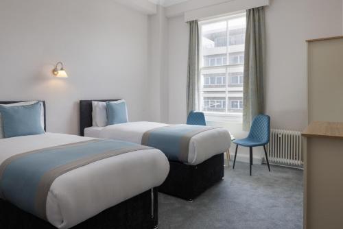 a hotel room with two beds and a window at The Cumberland Hotel in Eastbourne
