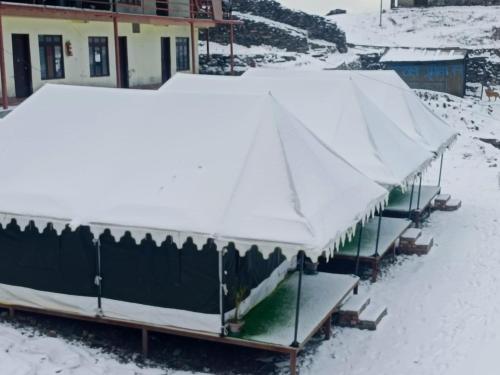two boats covered in snow in front of a house at Chopta Rock Hill Camp in Chopta