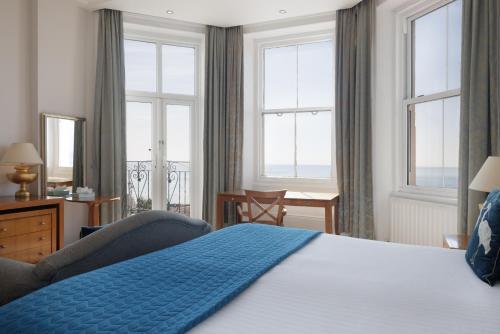 a bedroom with a bed with a blue blanket on it at The Cumberland Hotel in Eastbourne