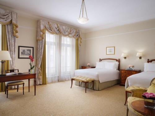 a hotel room with two beds and a desk at The Savoy in London