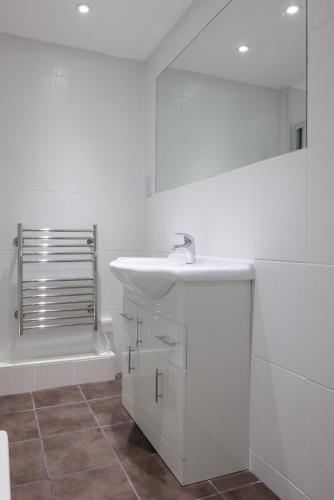 a white bathroom with a sink and a tub at The Cumberland Hotel in Eastbourne