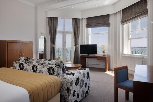 a hotel room with a bed and a couch and a television at The Cumberland Hotel in Eastbourne