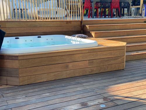 une baignoire jacuzzi assise sur une terrasse en bois dans l'établissement Villa Whaou 5*, piscine chauffée, jacuzzi, à Sémussac