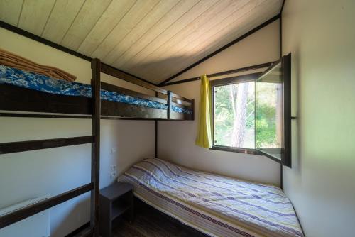 a small bedroom with two bunk beds and a window at Lou Gatoun - Cottage Climatisé in Solliès-Toucas