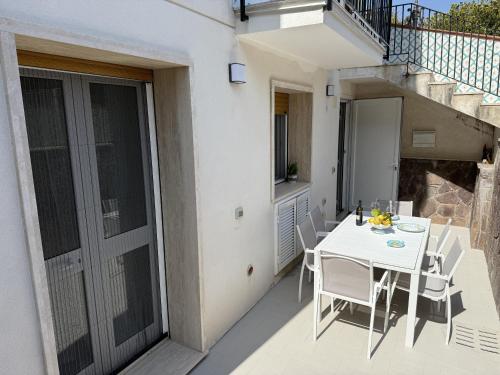 a balcony with a white table and chairs on a patio at Beach House Ponente in Erchie