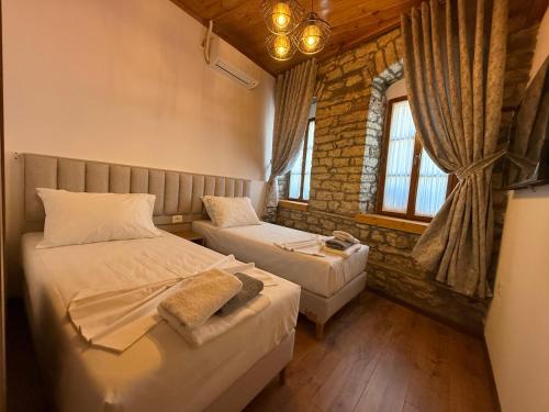 a bedroom with two beds and a window at Submarine 105 Rooms in Gjirokastër