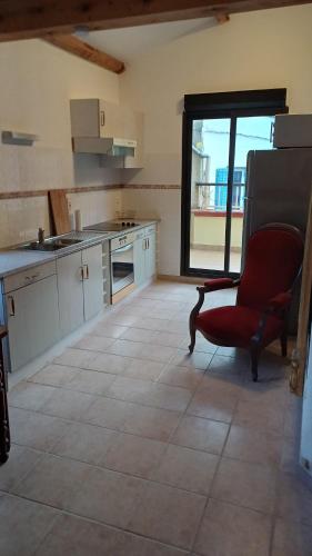 a kitchen with a red chair and a large window at Les Suites de Mauléon in Mauléon-Barousse