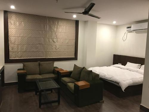 a bedroom with a bed and a couch and a chair at Hotel Rajmahal Inn in Gurgaon