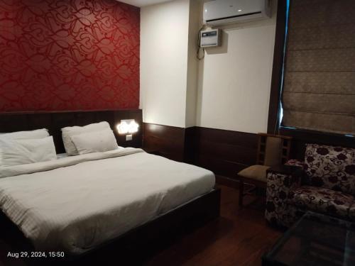 a hotel room with a bed and a chair at Hotel Rajmahal Inn in Gurgaon