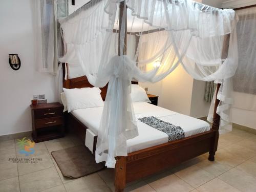 a bedroom with a canopy bed with white drapes at 1 bedroom suite Diani in Ukunda Airport