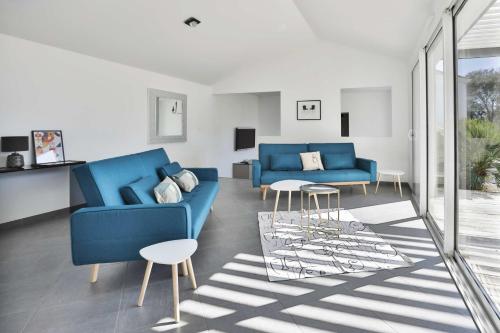 un salon avec deux canapés bleus et une table dans l'établissement Villa du Moulineau, à Les Sables-dʼOlonne