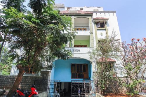 a blue and white house with a tree in front of it at Hotel O Krupa Service Apartments in Hyderabad