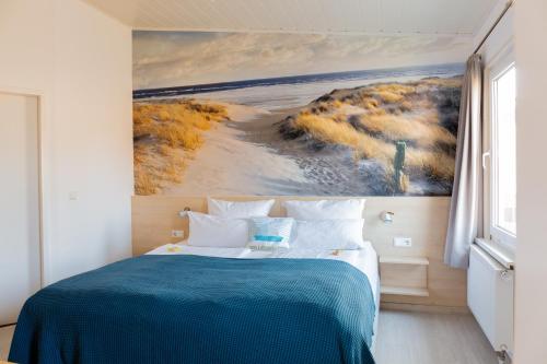 a bedroom with a bed with a painting on the wall at Hotel Bethanien in Langeoog