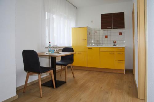a kitchen with yellow cabinets and a table and chairs at Hotel Rosenstein in Heubach
