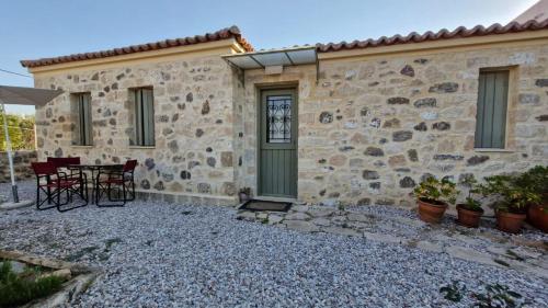 a stone house with a table and chairs outside at Jo's house in Aegina Town