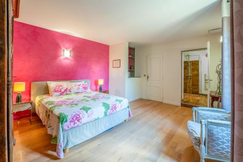 a bedroom with a bed and a pink wall at Maison d'hôte - La Colline in Solérieux