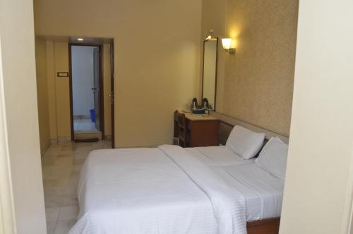 a bedroom with a large white bed and a mirror at Hotel Ashray International, Sion - Near BKC in Mumbai