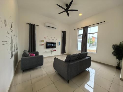 a living room with two chairs and a ceiling fan at Padang Serai Wangi Homestay 95 in Padang Serai
