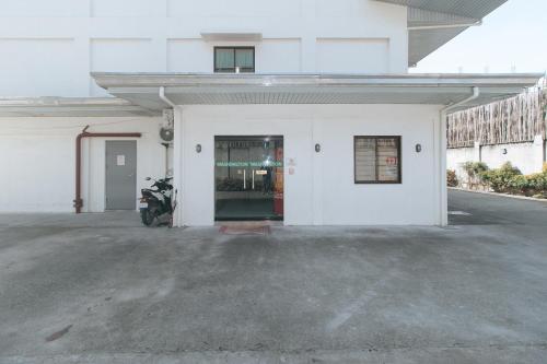 a white building with a motorcycle parked in a parking lot at RedDoorz @ Washington Guest House Olongapo in Olongapo