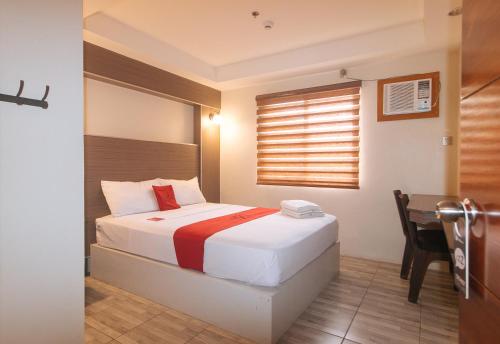 a bedroom with a bed with a desk and a window at RedDoorz @ Washington Guest House Olongapo in Olongapo