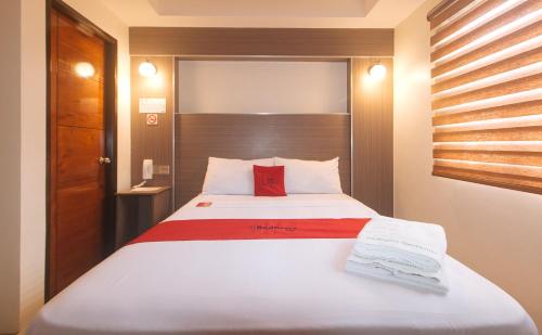 a bedroom with a large white bed with red pillows at RedDoorz @ Washington Guest House Olongapo in Olongapo