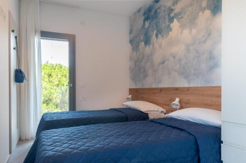two beds in a bedroom with a painting on the wall at One Life Suites in Bibione
