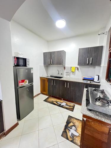 a kitchen with wooden cabinets and a stainless steel refrigerator at Diani Villa studio in Diani Beach