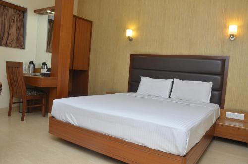 a bedroom with a large bed with a desk and a table at Hotel Ashray International, Sion - Near BKC in Mumbai