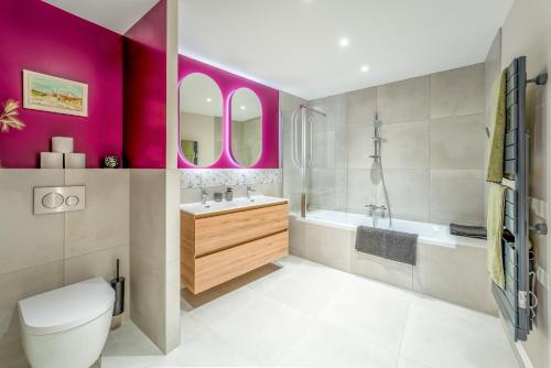 a bathroom with pink walls and a toilet and a sink at Maison d'hôte - La Colline in Solérieux