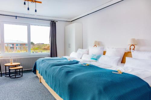 a bedroom with a large bed with a blue blanket at Hotel Bethanien in Langeoog