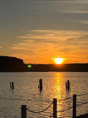 a sunset over a body of water with a dock at Romantic apartment in Ruciane in Ruciane-Nida