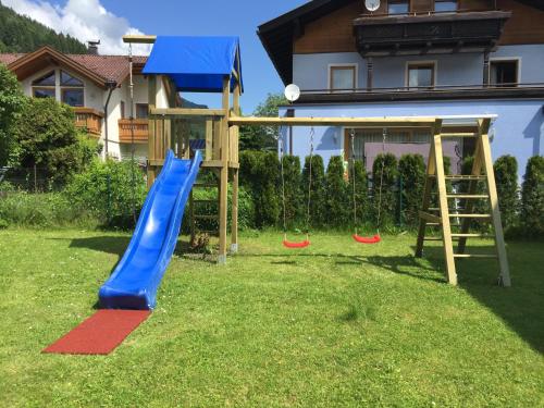un patio con un parque infantil con tobogán y columpios en Haus Vera en Zell am See