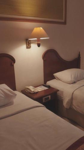 a hotel room with two beds and a table with a lamp at People Tours Bukhara in Muruntau