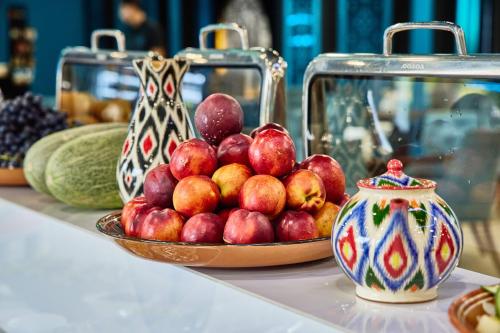 a bowl of apples on a table next to a vase at Hotel Uzbekistan in Tashkent