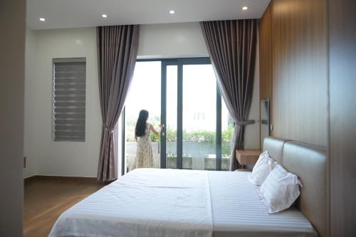 une femme qui regarde par la fenêtre d'une chambre d'hôtel dans l'établissement Peace Villa, à Dong Quan
