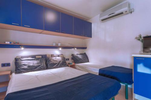 a small room with two beds and blue cabinets at Camping Village Cavallino in Cavallino-Treporti