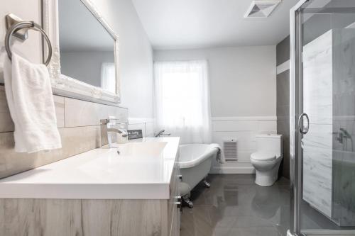 a bathroom with a tub and a sink and a toilet at Lake and Pool Table - Au Pied du Lac in Labelle