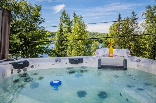 a hot tub with a bottle of wine in it at Lake and Pool Table - Au Pied du Lac in Labelle