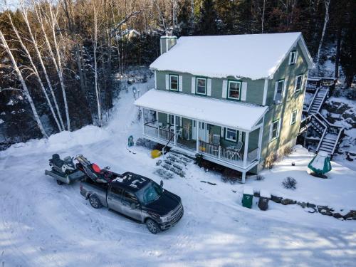 a truck parked in front of a house in the snow at Lake and Pool Table - Au Pied du Lac in Labelle