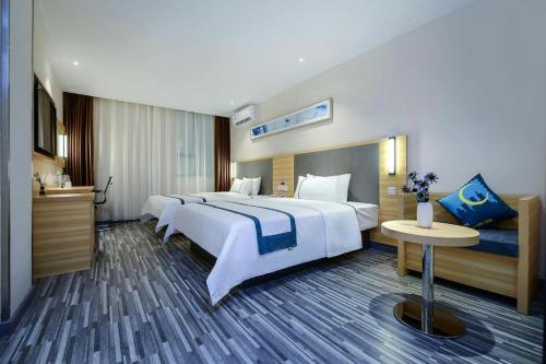 Cette grande chambre comprend 2 lits et une table. dans l'établissement City Comfort Inn Chongqing Southwest University Beibei Metro Station, à Huangjuezhen