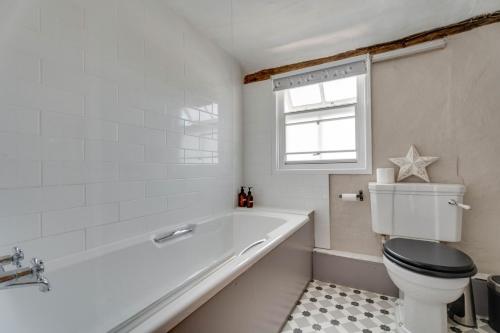 ein Badezimmer mit Badewanne und Toilette und einem Fenster in der Unterkunft Winter Cottage, Clare in Clare