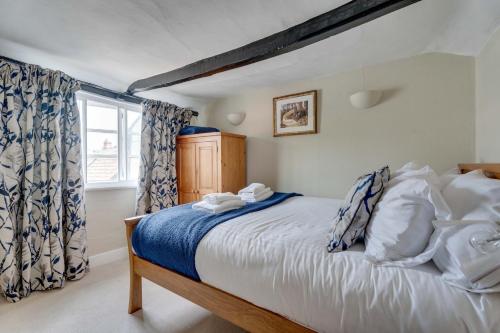 Schlafzimmer mit einem Bett mit blauer und weißer Bettwäsche und einem Fenster in der Unterkunft Winter Cottage, Clare in Clare