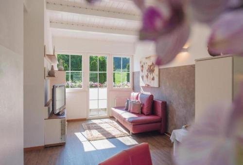 a living room with a red couch and a tv at Gartenhof in Brixen