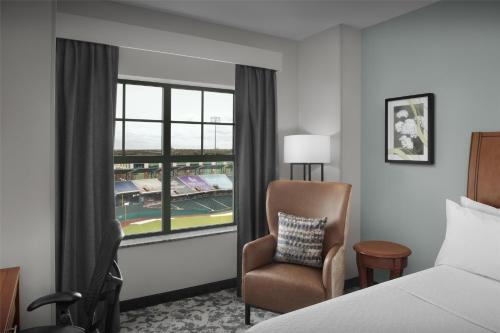 a bedroom with a bed and a chair and a window at Hilton Garden Inn Oklahoma City/Bricktown in Oklahoma City